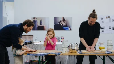 Foto: Pastaworkshop, zwei Erwachsene und zwei Kinder formen Pasta an einem Tisch.