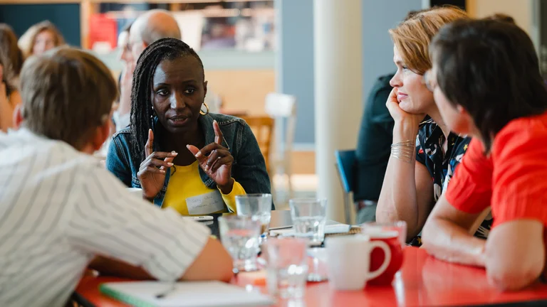Four people sit around a table and talk to each other during a workshop