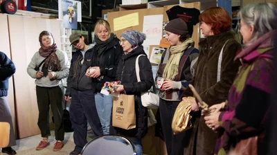 Women are standing in a workshop holding various objects in their hands