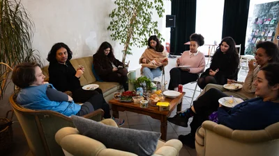 A group of people are sitting around a table, chatting.