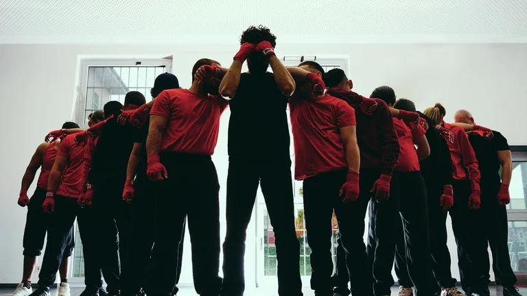 Young men hook each other, cover their faces with their fists