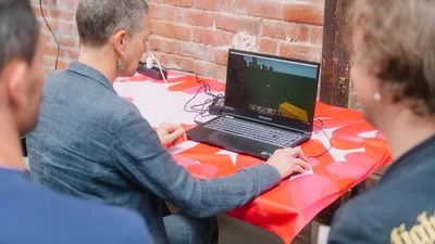 eine Person vor einem Laptop, die anderen schauen ihr über die Schulter