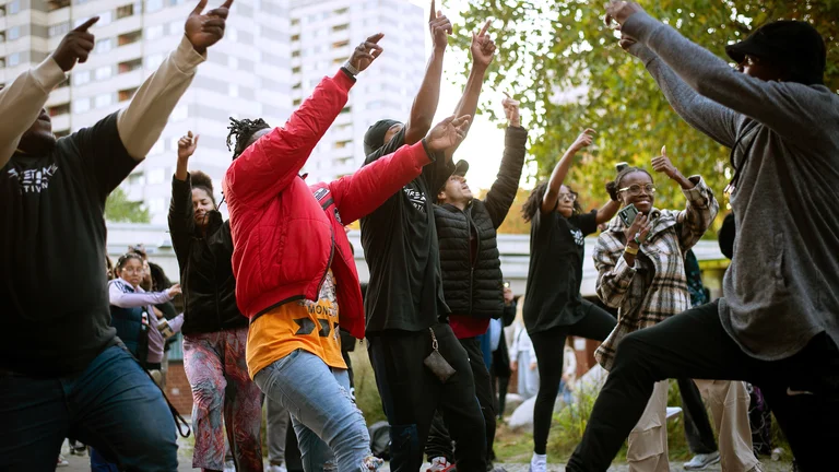 A group of PoC are outside in a park dancing together.