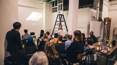 Several people are watching a video projected onto a wall