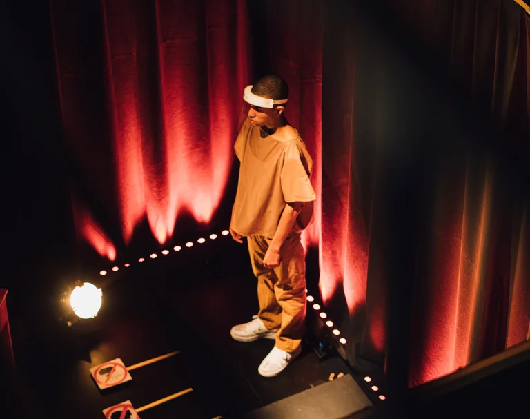 Top view of a young man standing behind a curtain in a dark room