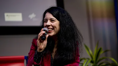 Rita Rinaldo lächelt während sie ein Mikro in der Hand hält