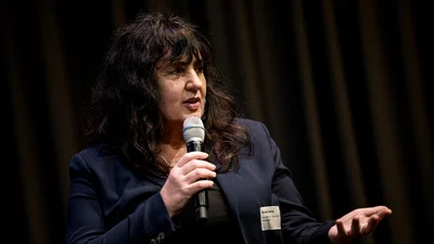 Eine Frau im Blazer mit lockigen langen Haaren